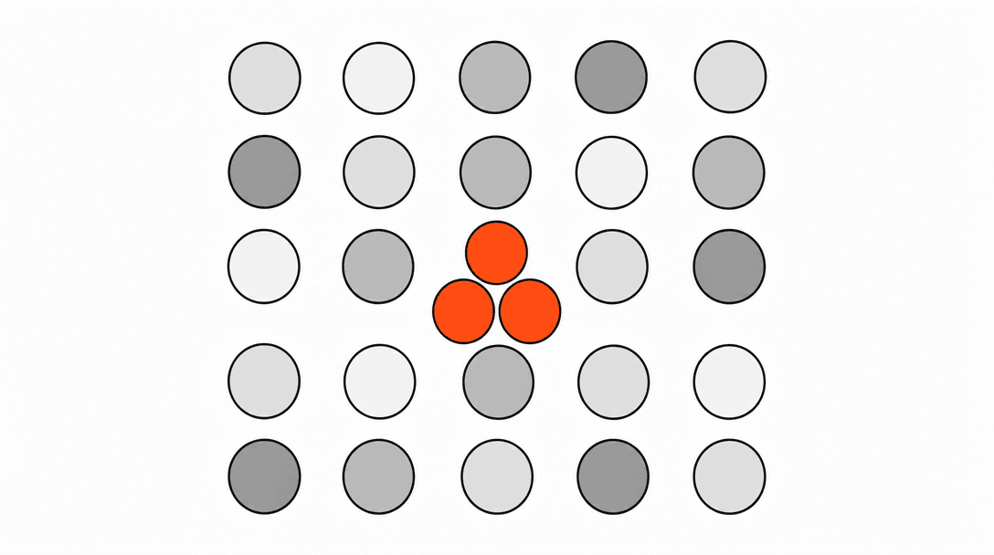 A flat grid of small circles on a white background, each a slightly different shade of grey, with one cluster of three circles filled solid orange at the center